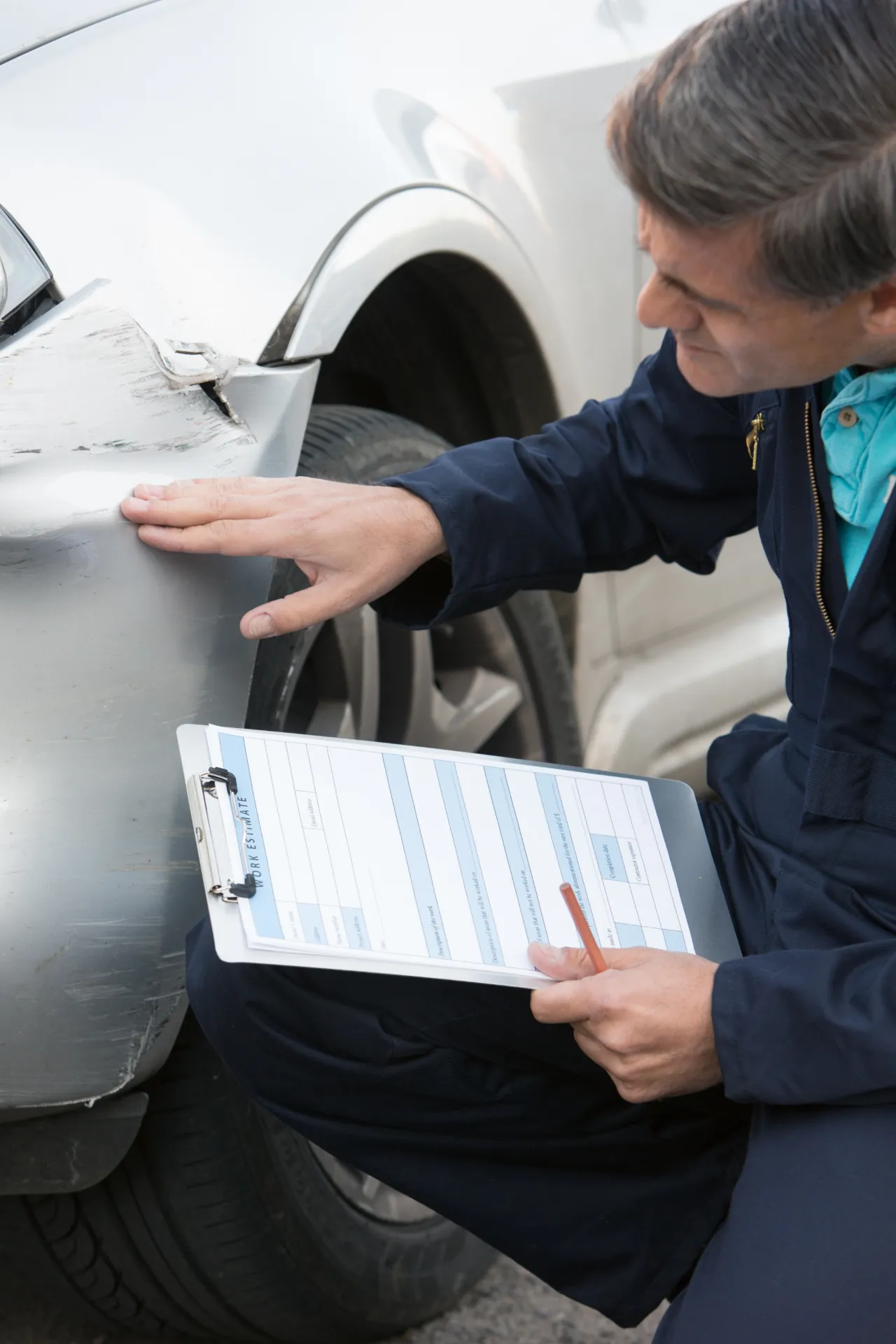 Mann der den Schaden am Auto überprüft und Notizen macht
