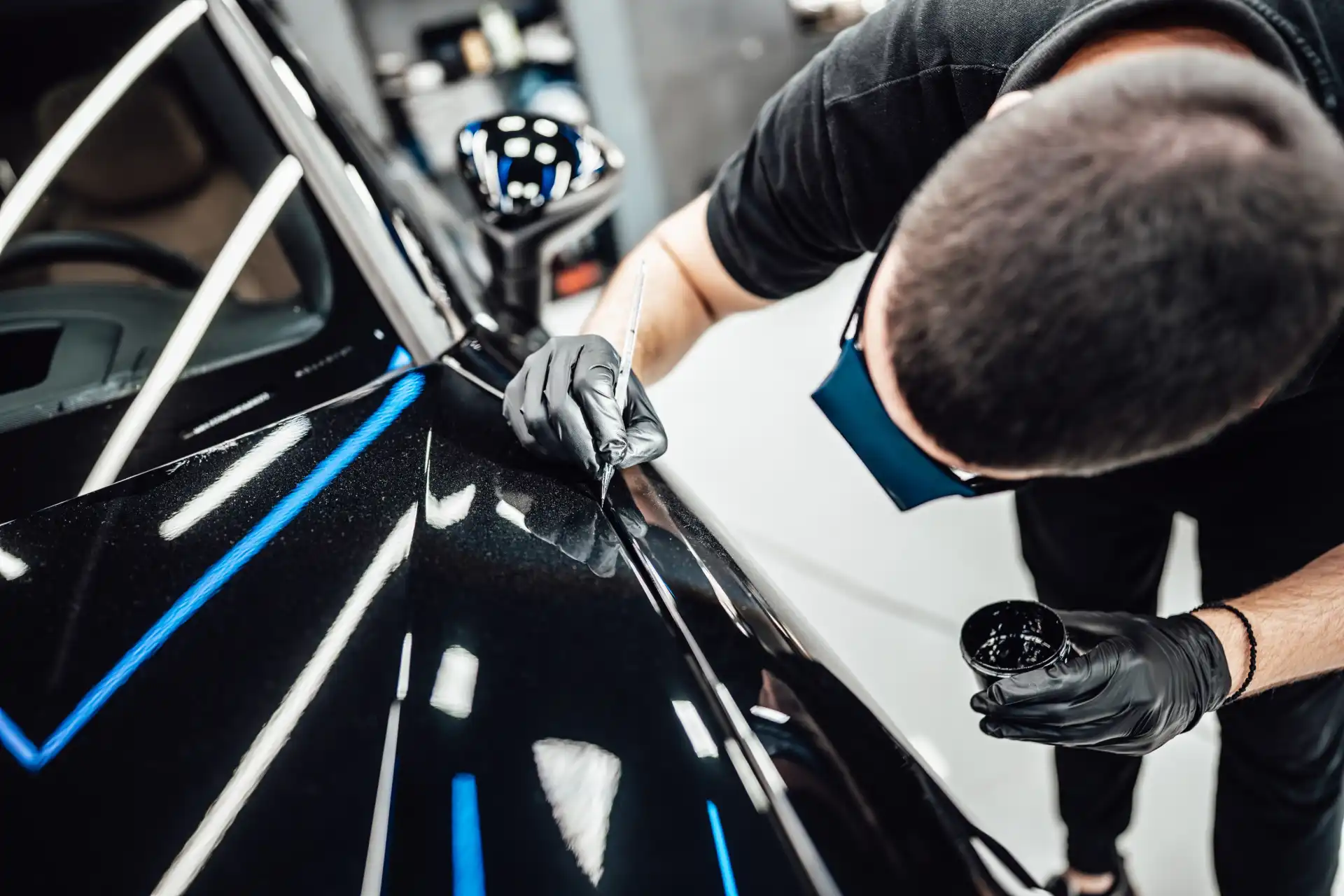 Mitarbeiter der einen Kratzer am Auto mit einem Stift lackiert (Smart Repair)